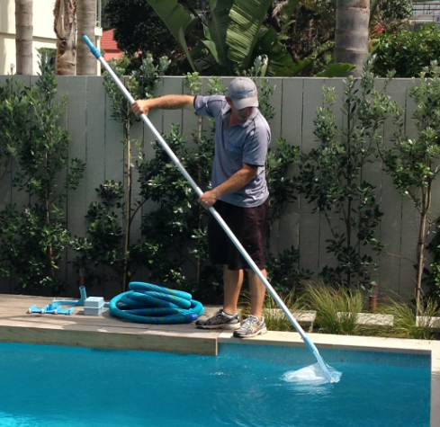 guy using pool cleaning equipment-pool maintenance services-Swimmingly Pools