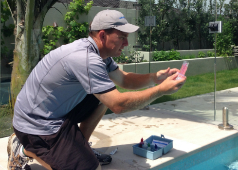 person checking pool water results-pool maintenance services-Swimmingly Pools